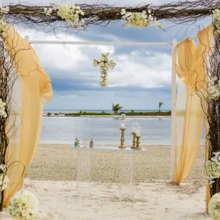 Beachfront wedding ceremony arch with gold fabric at El Dorado Maroma, Riviera Maya