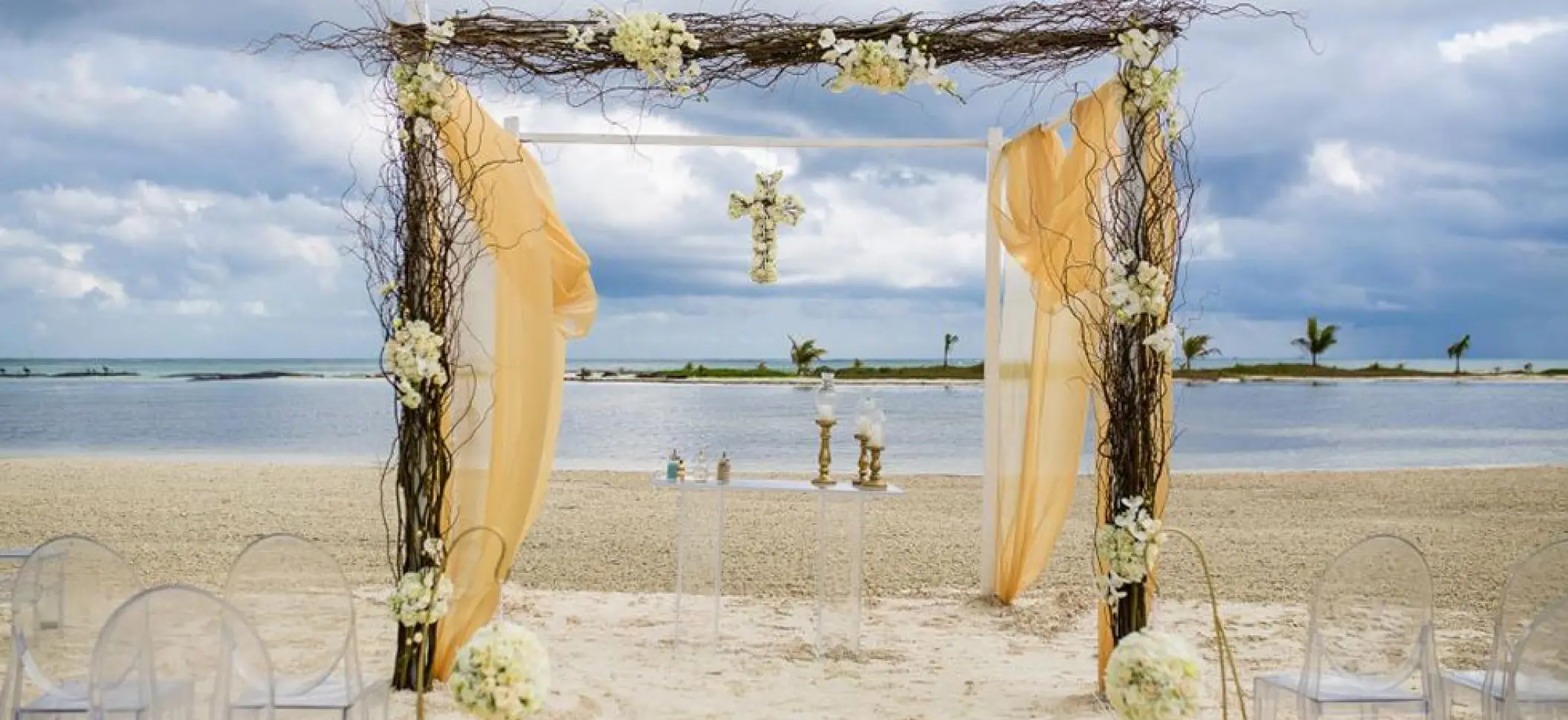 Beachfront wedding ceremony arch with gold fabric at El Dorado Maroma, Riviera Maya