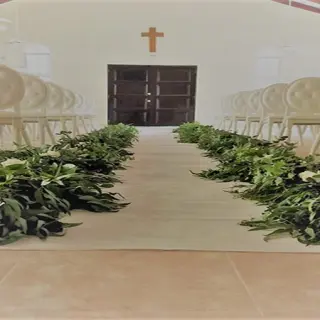 Chapel wedding ceremony setup with greenery lining the aisle at El Dorado Maroma, Riviera Maya