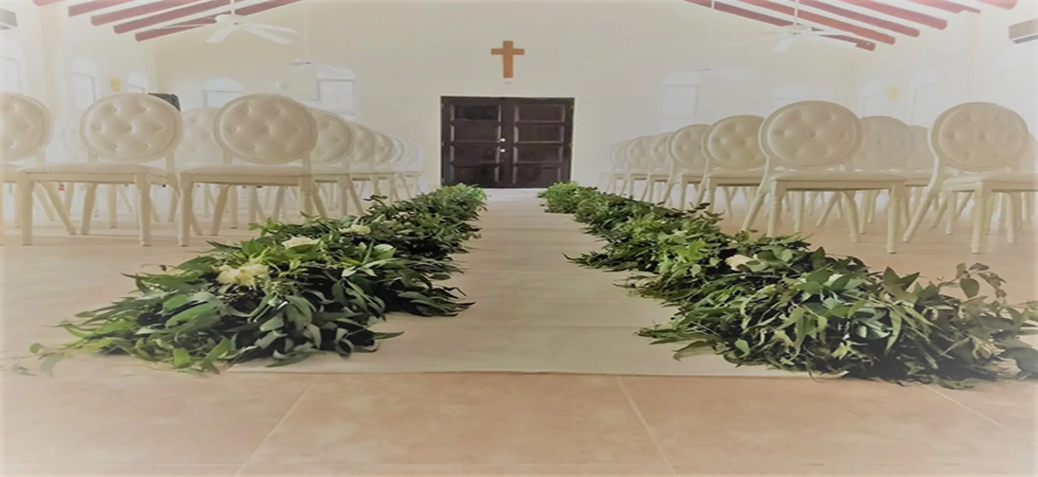Chapel wedding ceremony setup with greenery lining the aisle at El Dorado Maroma, Riviera Maya