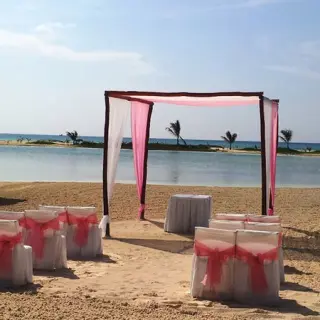 Beachfront wedding ceremony with a pink and white huppah at El Dorado Maroma, Riviera Maya