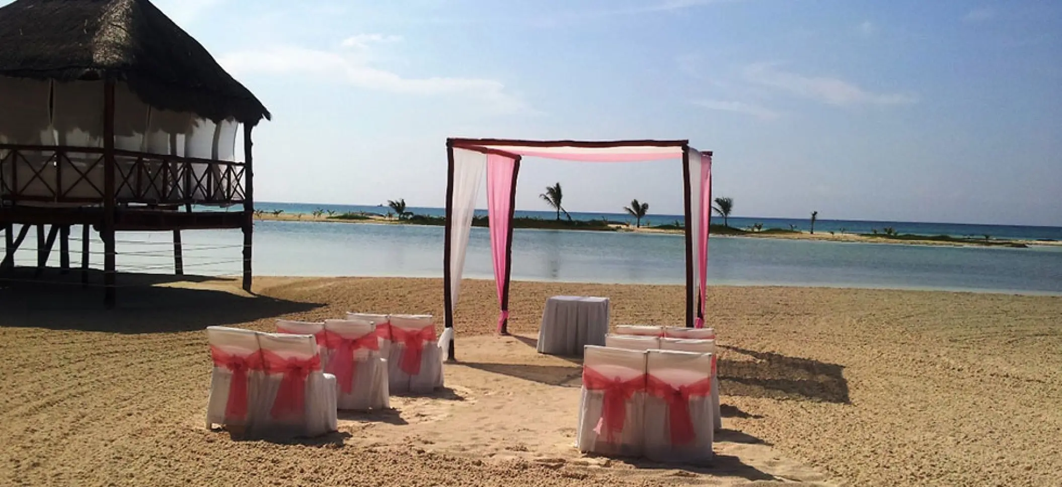 Beachfront wedding ceremony with a pink and white huppah at El Dorado Maroma, Riviera Maya