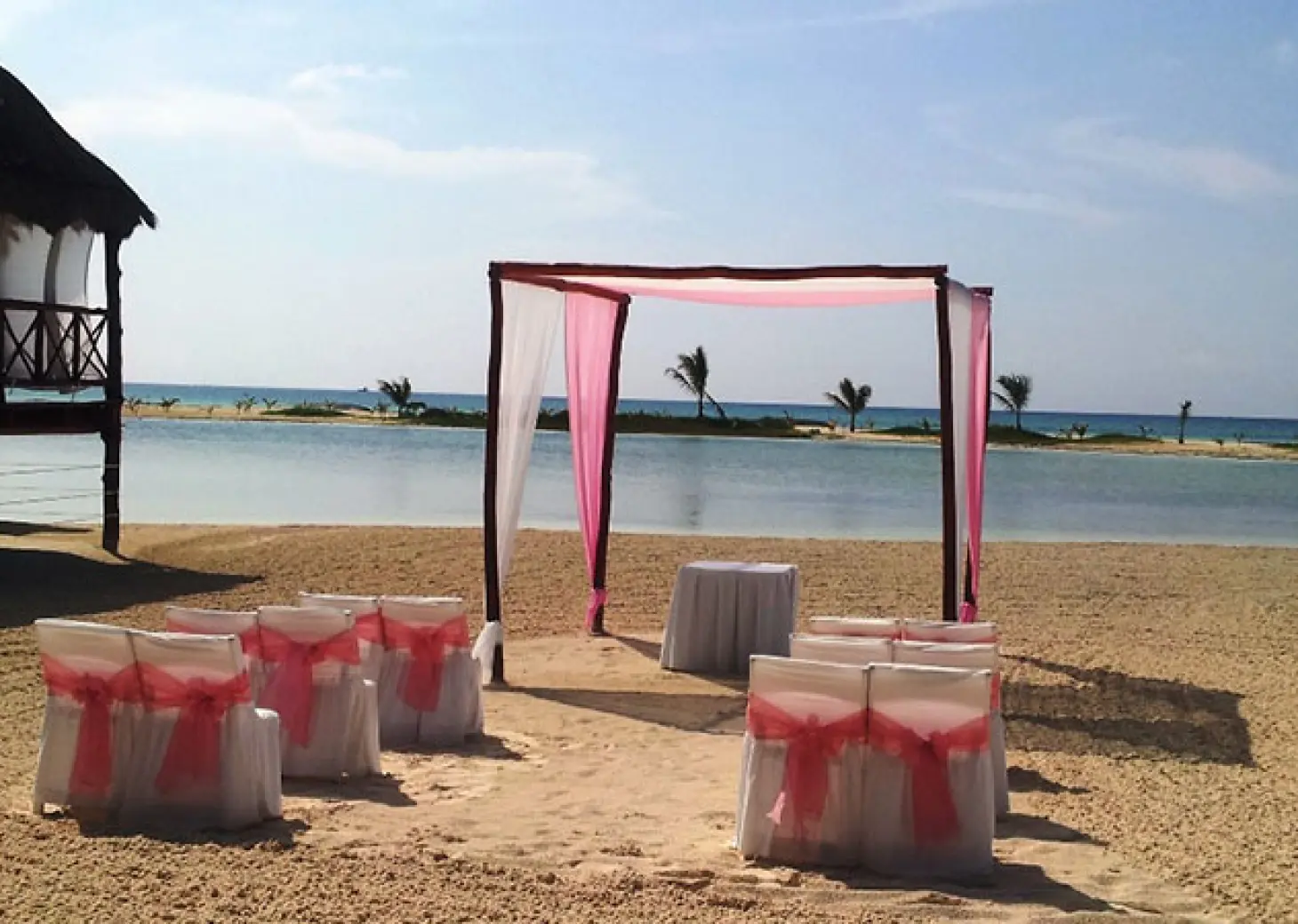 Beachfront wedding ceremony with a pink and white huppah at El Dorado Maroma, Riviera Maya