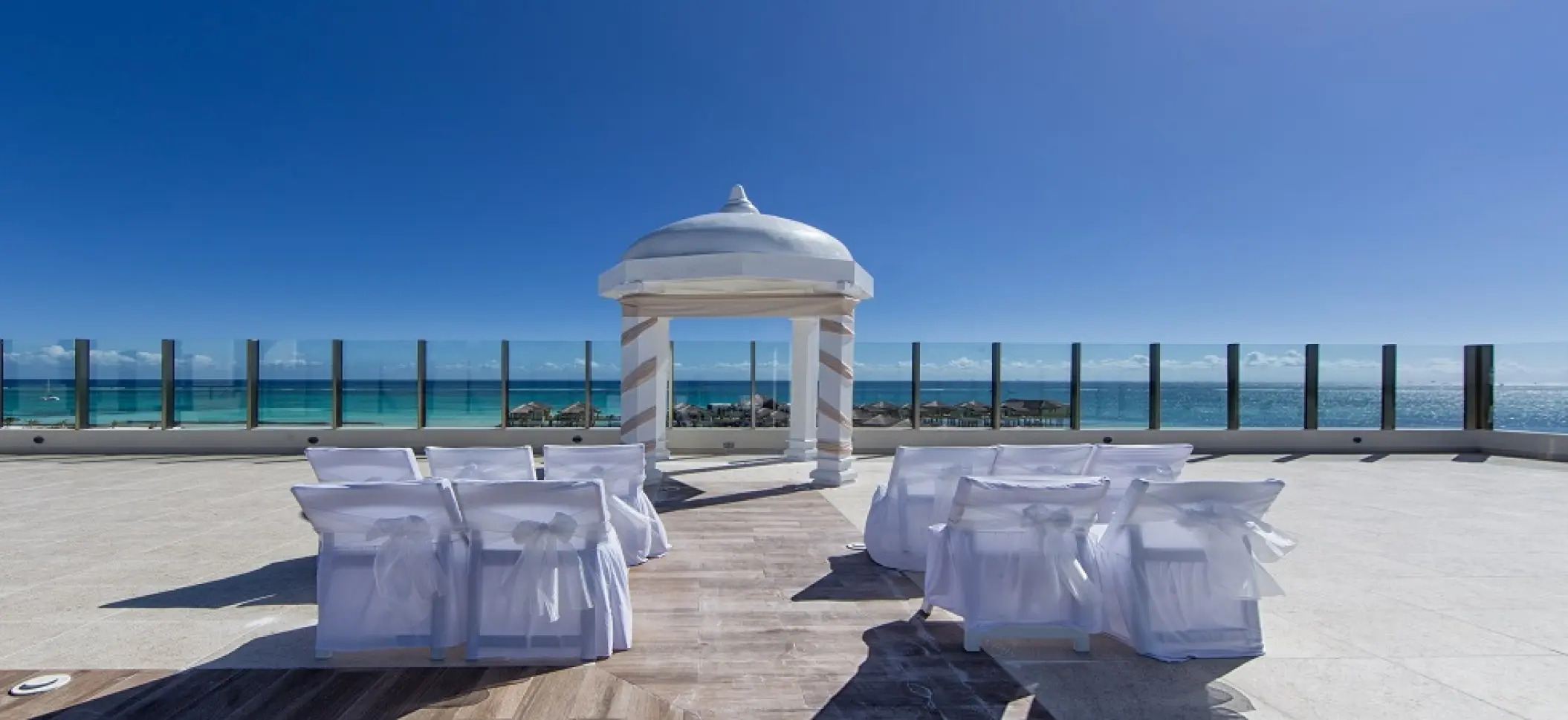 Palafitos Sky Deck wedding ceremony setup with white gazebo and chairs at El Dorado Maroma, Riviera Maya