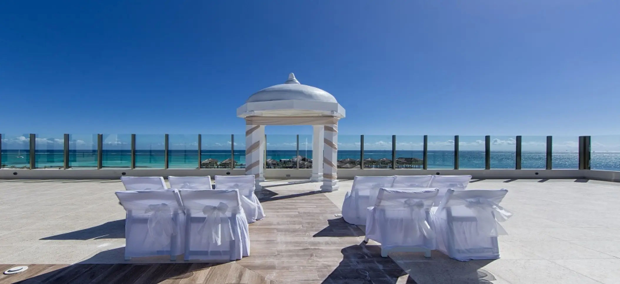 Palafitos Sky Deck wedding ceremony setup with white gazebo and chairs at El Dorado Maroma, Riviera Maya