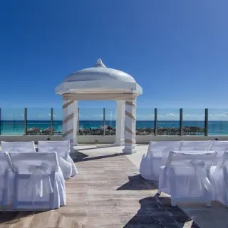 Palafitos Sky Deck wedding ceremony setup with white gazebo and chairs at El Dorado Maroma, Riviera Maya