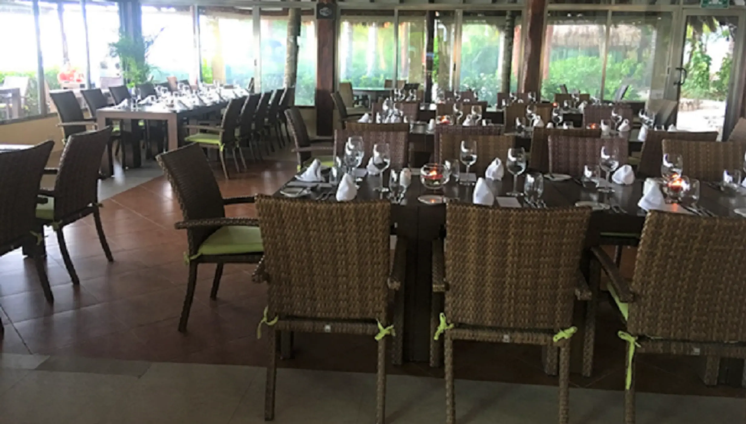 Indoor wedding reception setup with wicker chairs and set tables at El Dorado Maroma, Riviera Maya