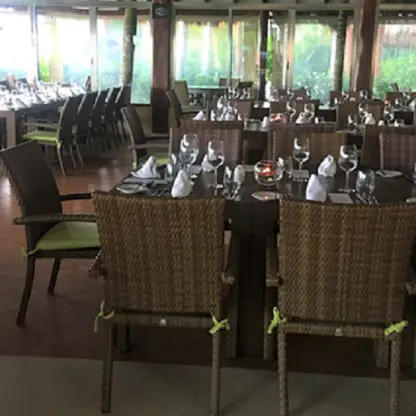 Indoor wedding reception setup with wicker chairs and set tables at El Dorado Maroma, Riviera Maya