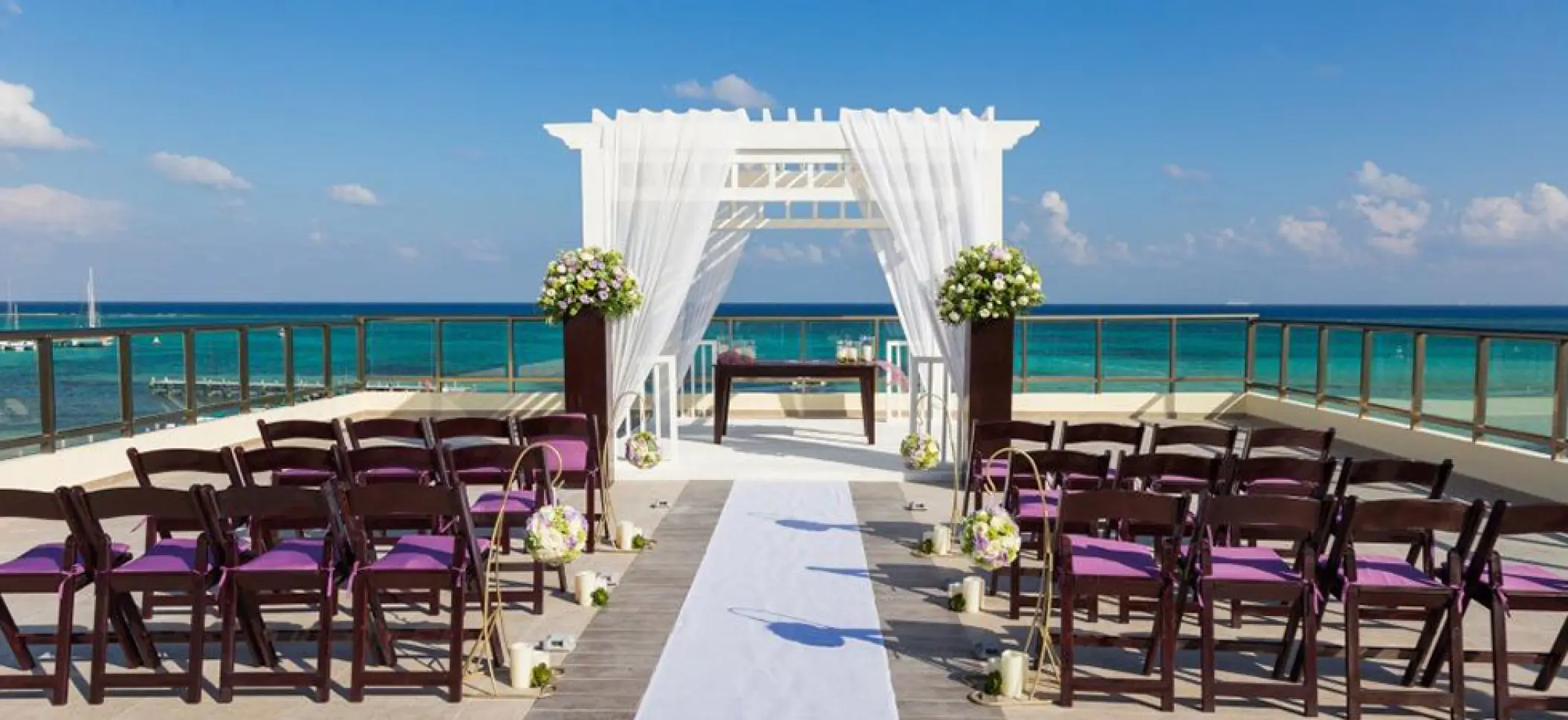 Sky deck wedding ceremony with purple chairs and white pergola at El Dorado Maroma, Riviera Maya