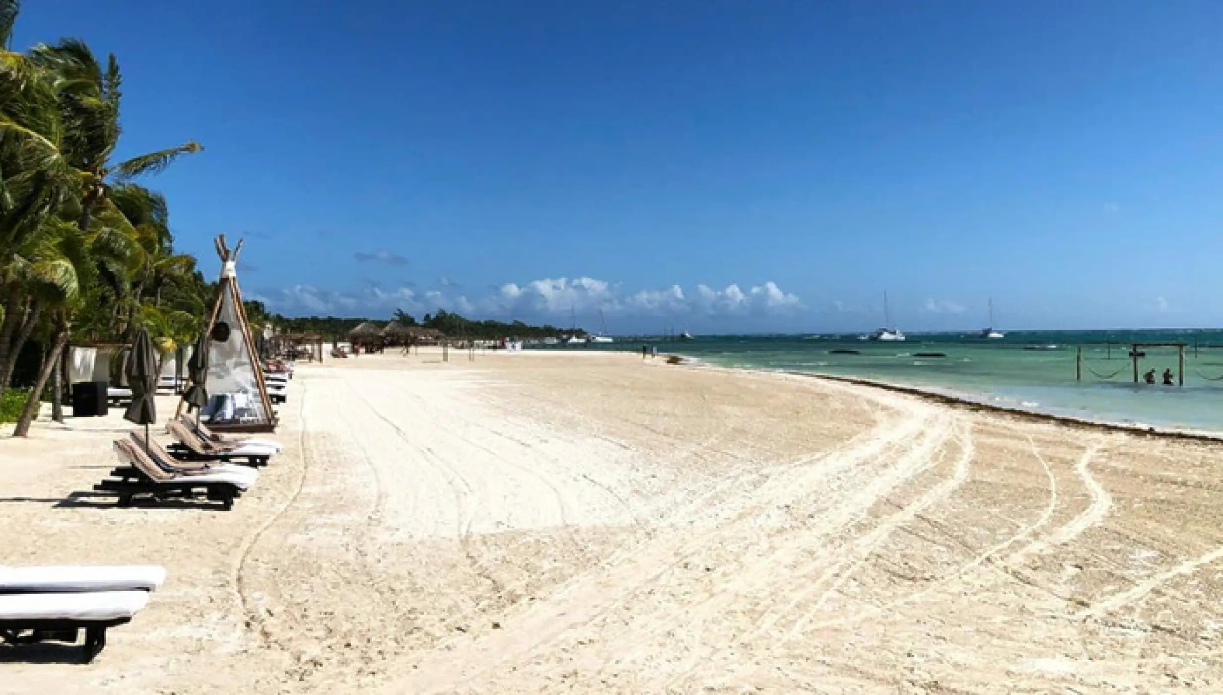 White sand beach with lounge chairs and palm trees at El Dorado Maroma, Riviera Maya