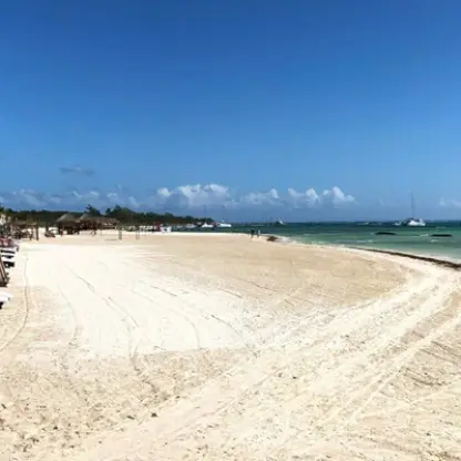 White sand beach with lounge chairs and palm trees at El Dorado Maroma, Riviera Maya