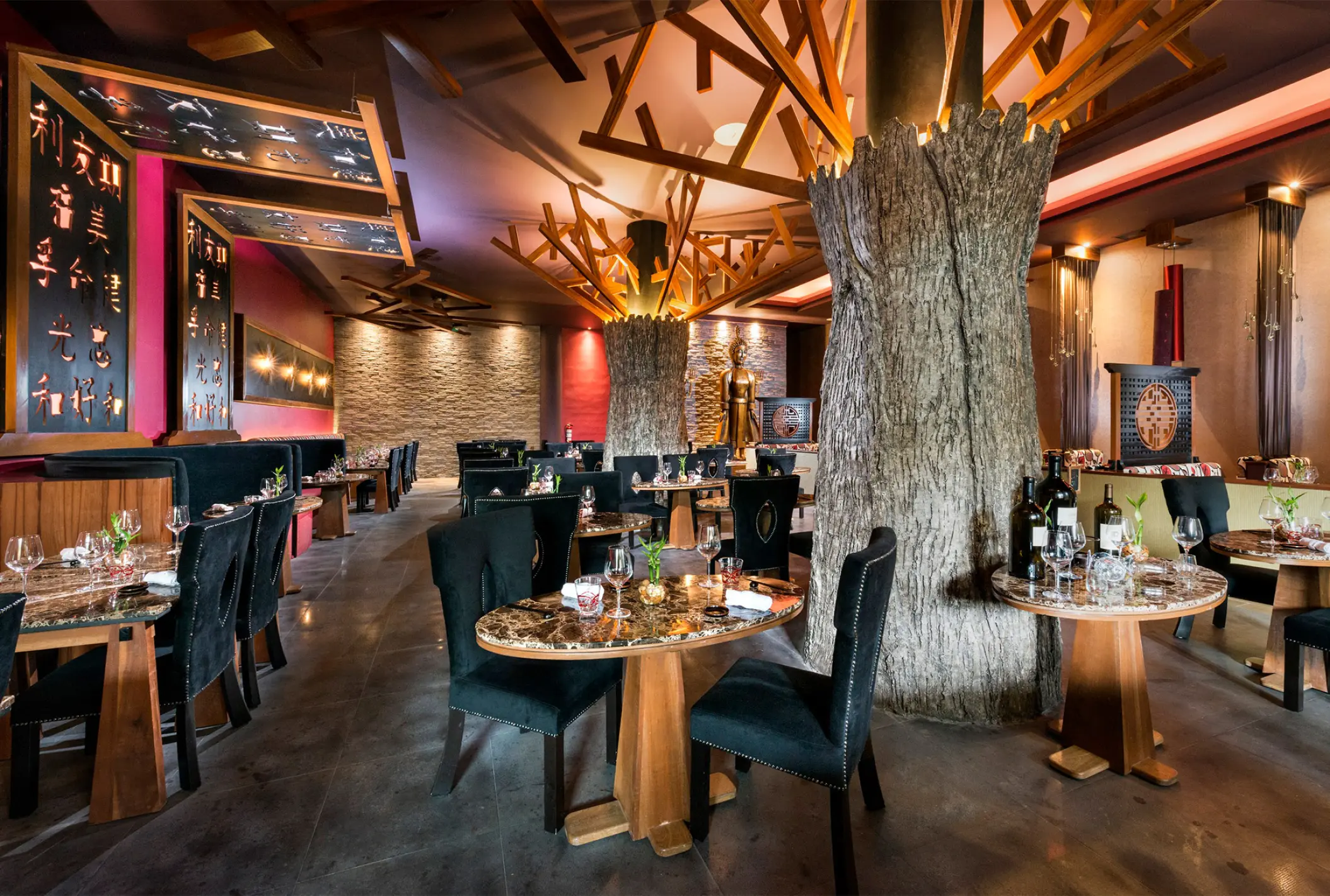 Indoor restaurant with tree-trunk columns and stone walls at El Dorado Seaside Palms, Riviera Maya