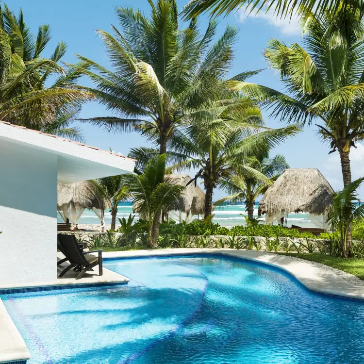 El Dorado Seaside Palms outdoor pool surrounded by palm trees and palapas, Riviera Maya