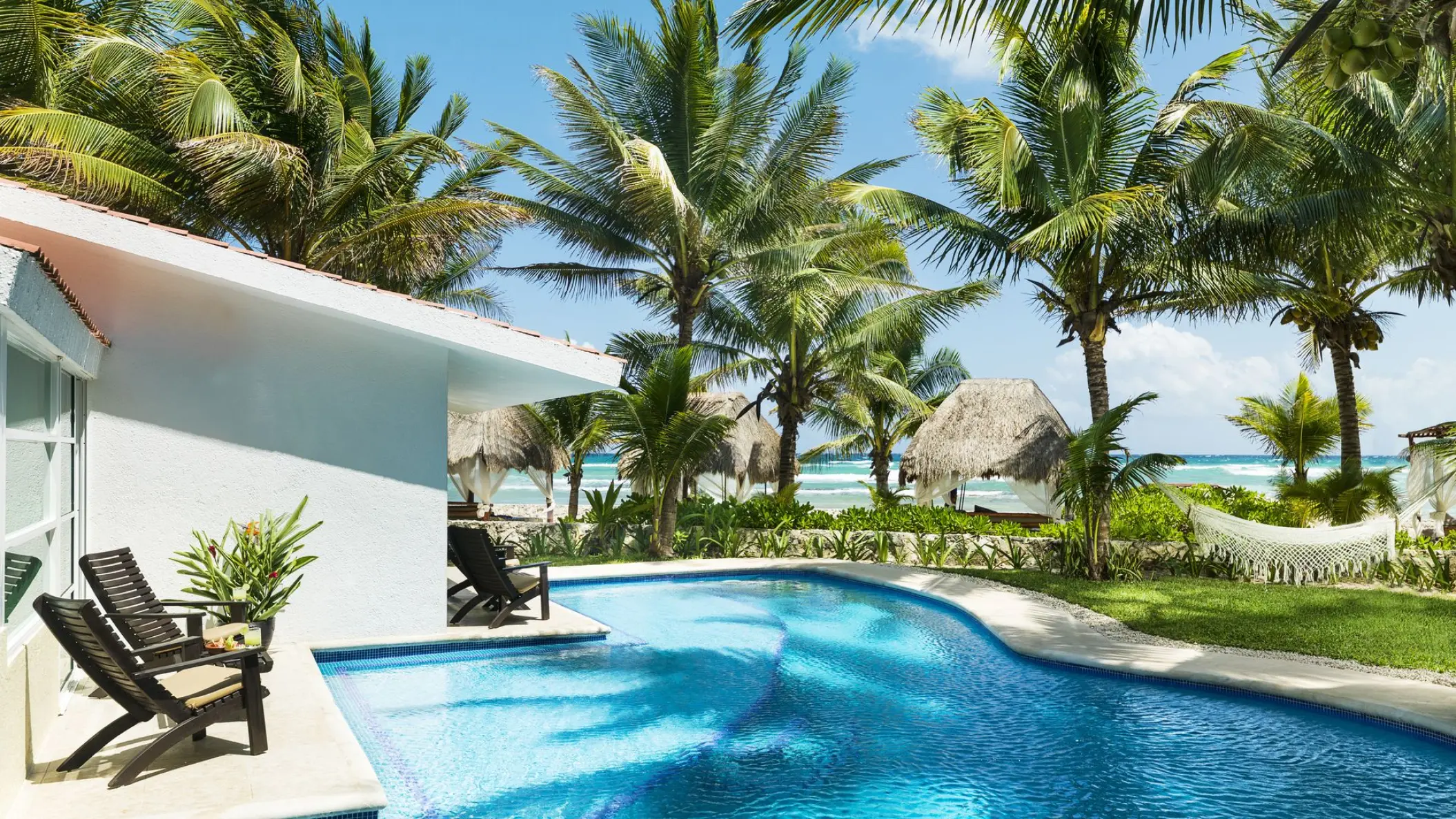 El Dorado Seaside Palms outdoor pool surrounded by palm trees and palapas, Riviera Maya