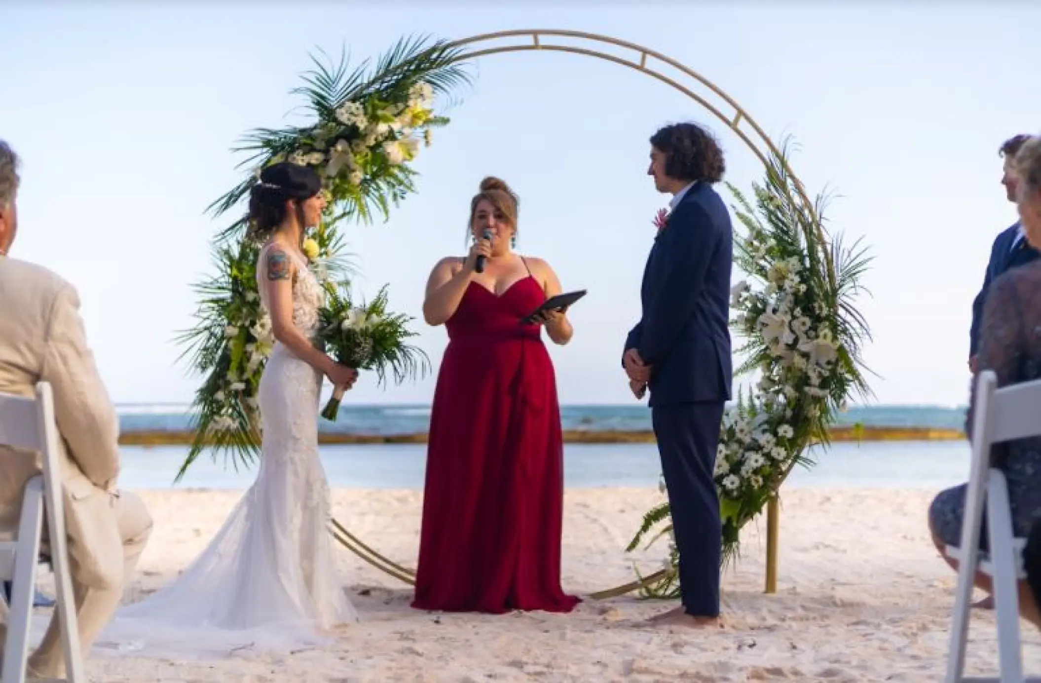 Beachfront wedding ceremony with a circular gold floral arch at El Dorado Seaside Palms, Riviera Maya