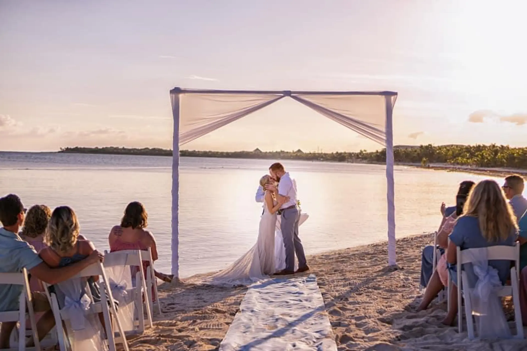 The couple kissing during a beach ceremony at El Dorado Seaside Palms, Riviera Maya