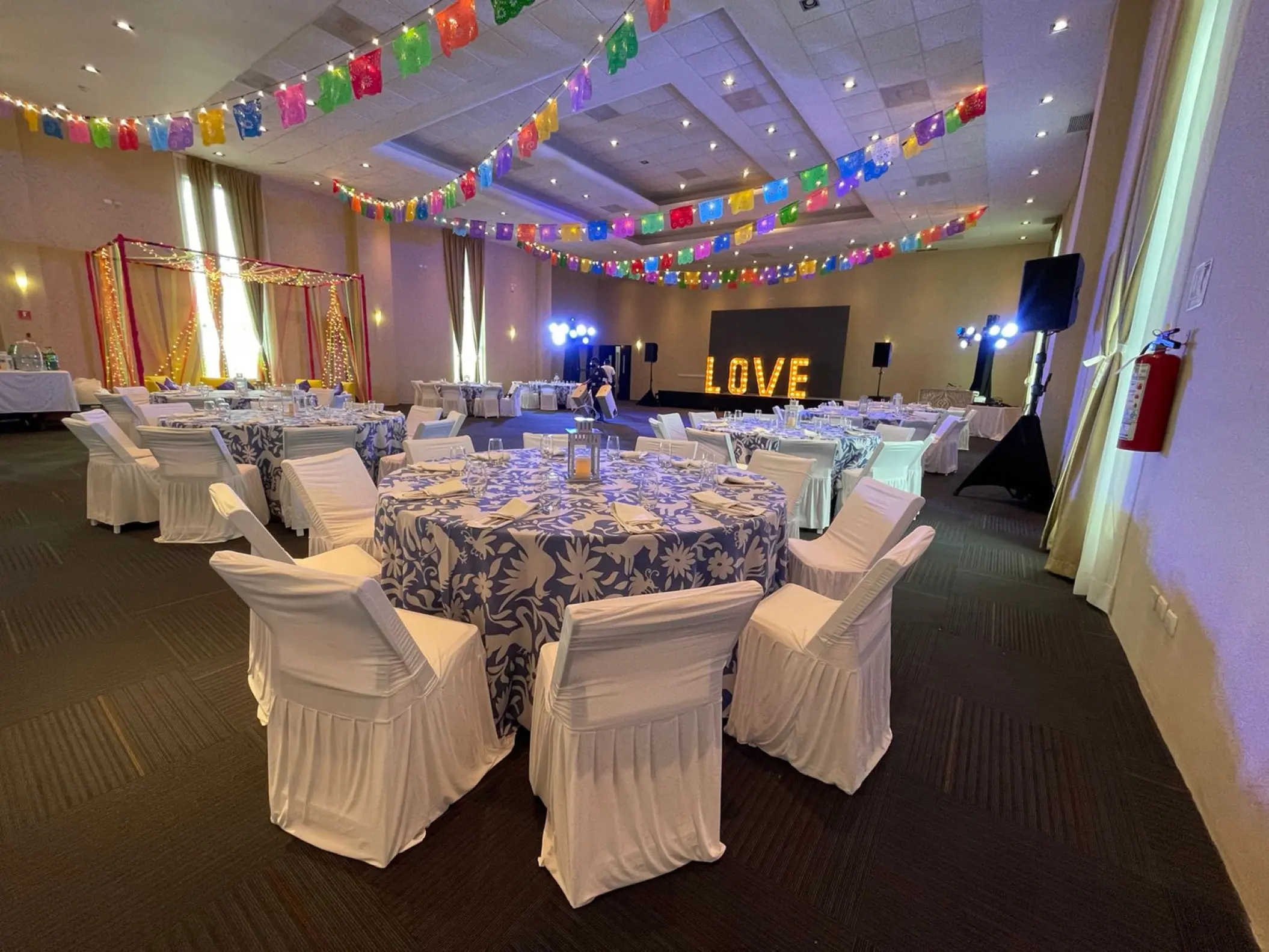 Indoor wedding reception with colorful banners and LOVE sign at El Dorado Seaside Palms, Riviera Maya