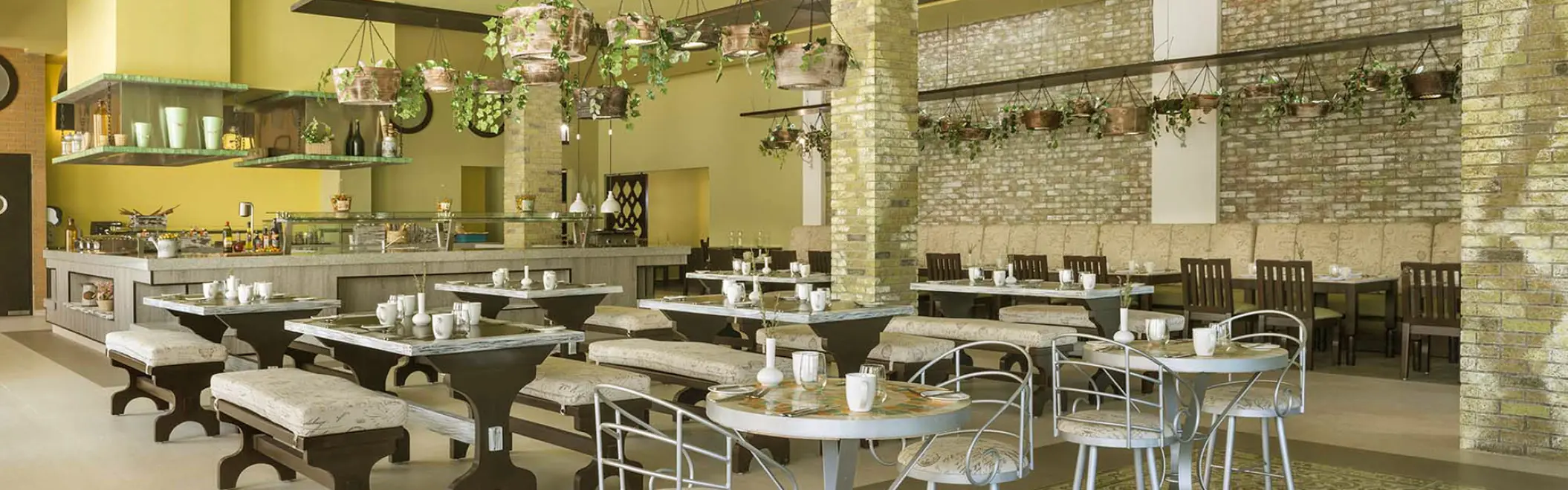 Indoor restaurant dining area with hanging plants and stone pillars at El Dorado Seaside Palms, Riviera Maya