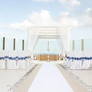 Sky deck wedding ceremony with white gazebo and blue-ribboned chairs at El Dorado Seaside Palms, Riviera Maya
