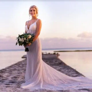 Bride holding a bouquet on a stone pier during sunset at El Dorado Seaside Palms, Riviera Maya