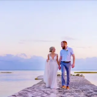 Bride and groom walking along a stone pier at sunset at El Dorado Seaside Palms, Riviera Maya