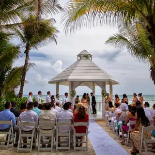 White gazebo wedding ceremony framed by palm trees at El Dorado Seaside Palms, Riviera Maya