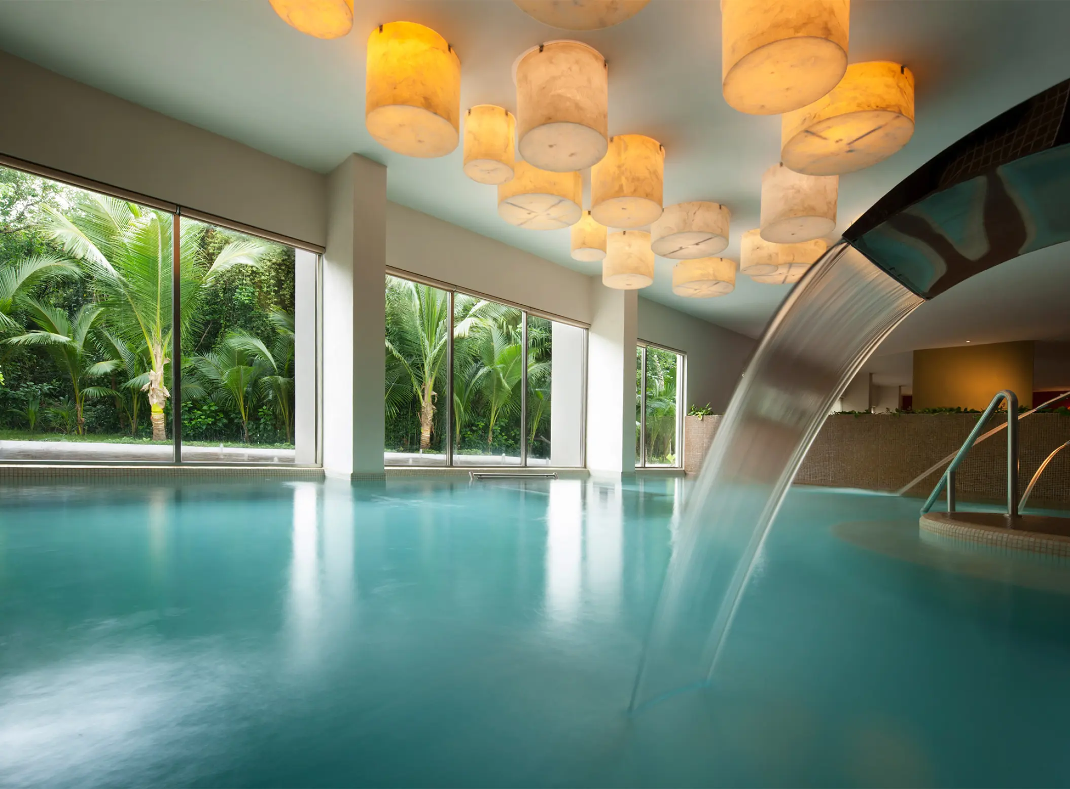 Indoor hydrotherapy pool with water feature and glowing lanterns at El Dorado Seaside Palms, Riviera Maya