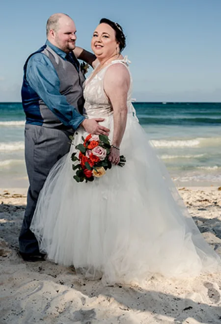 Groom and bride pose for a shot on the beach
