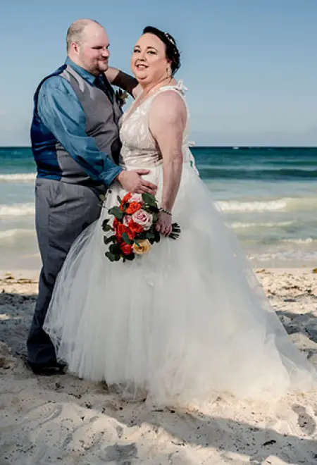 Erica & Alex smiling on the beach in their wedding attire