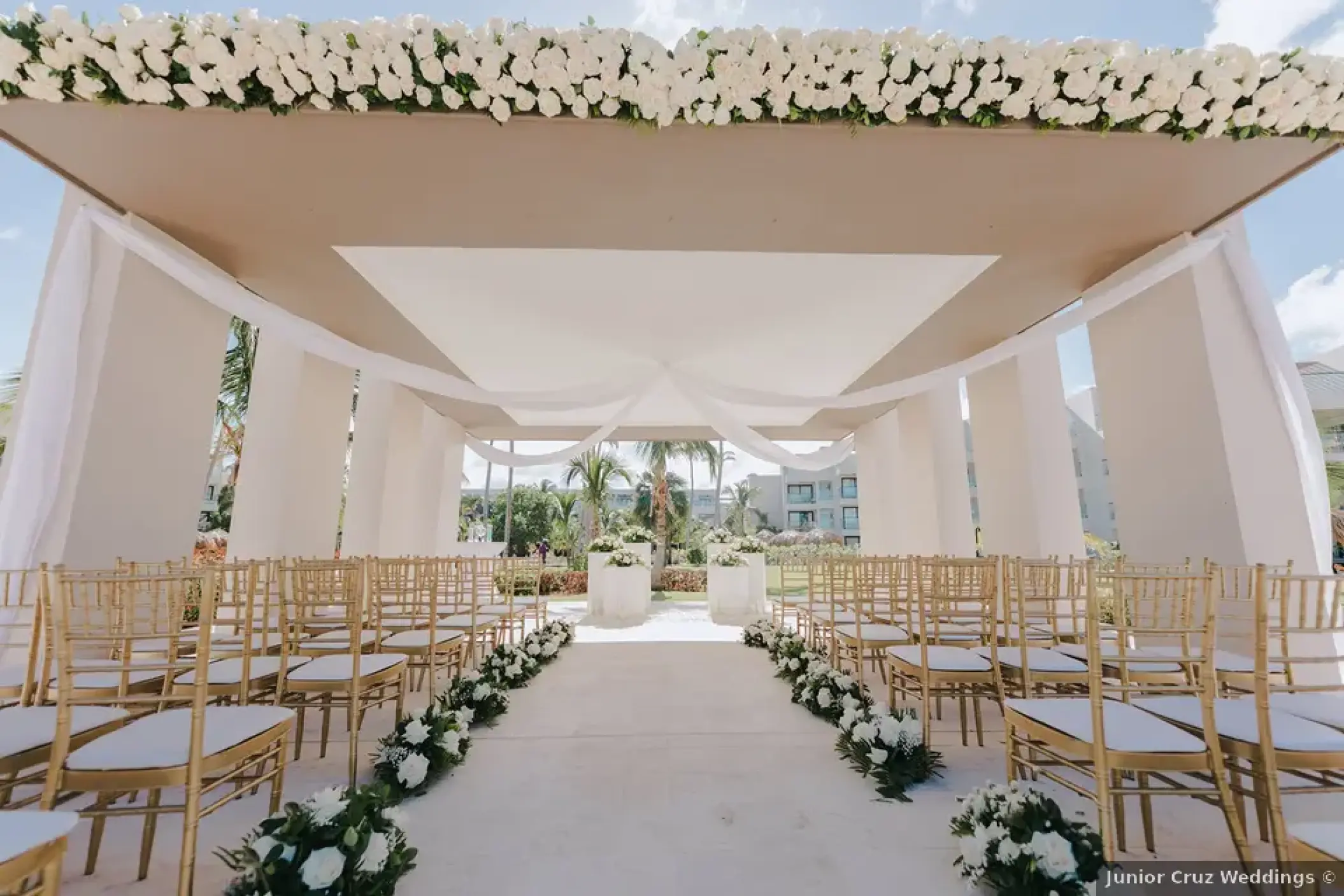 Modern gazebo wedding ceremony with gold chairs and white flowers at Excellence El Carmen, Punta Cana