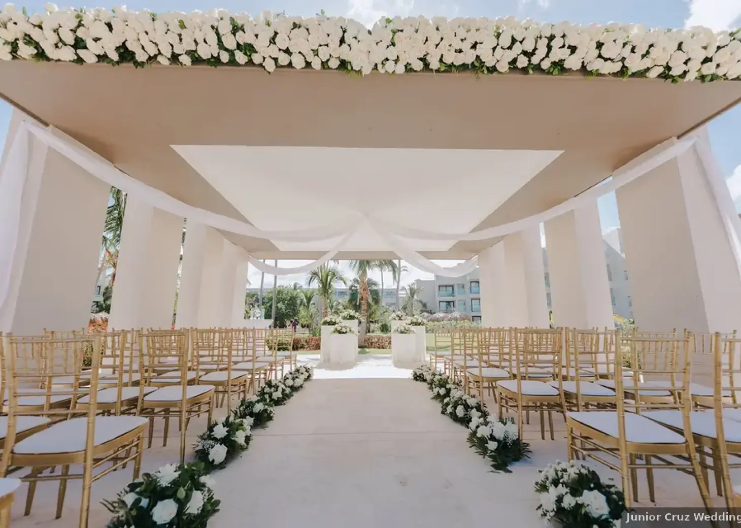 Modern gazebo wedding ceremony with gold chairs and white flowers at Excellence El Carmen, Punta Cana