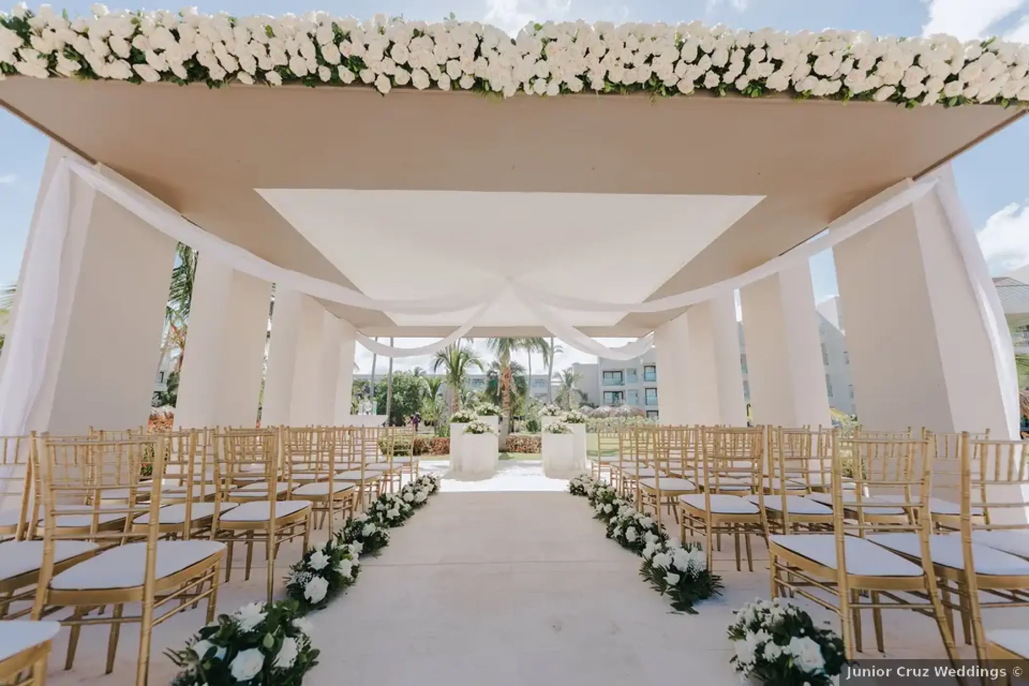 Modern gazebo wedding ceremony with gold chairs and white flowers at Excellence El Carmen, Punta Cana