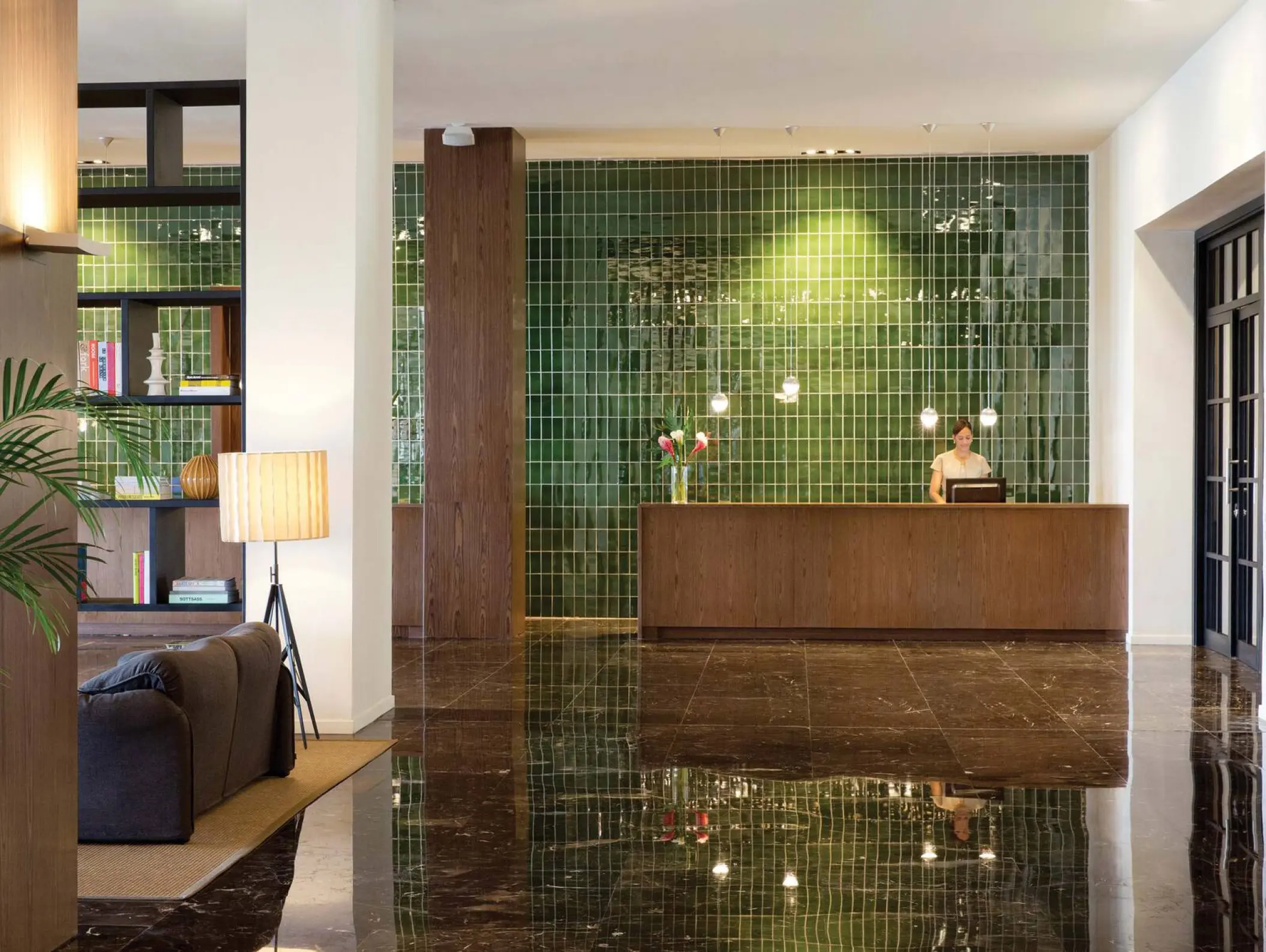 Modern lobby with a green tiled feature wall and wooden reception desk at Excellence El Carmen, Punta Cana