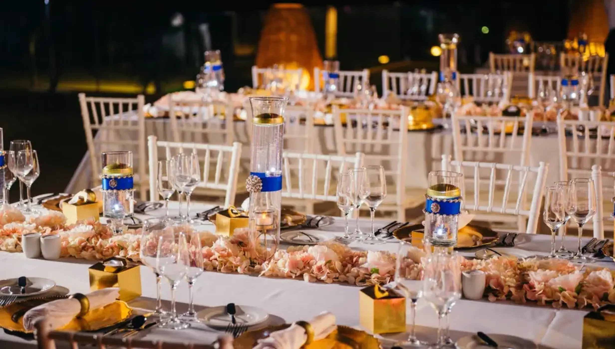 Outdoor wedding reception tables with gold chargers and blue accents at Excellence El Carmen, Punta Cana