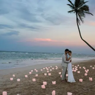 The bride and groom embracing on a beach with lanterns at Excellence El Carmen, Punta Cana