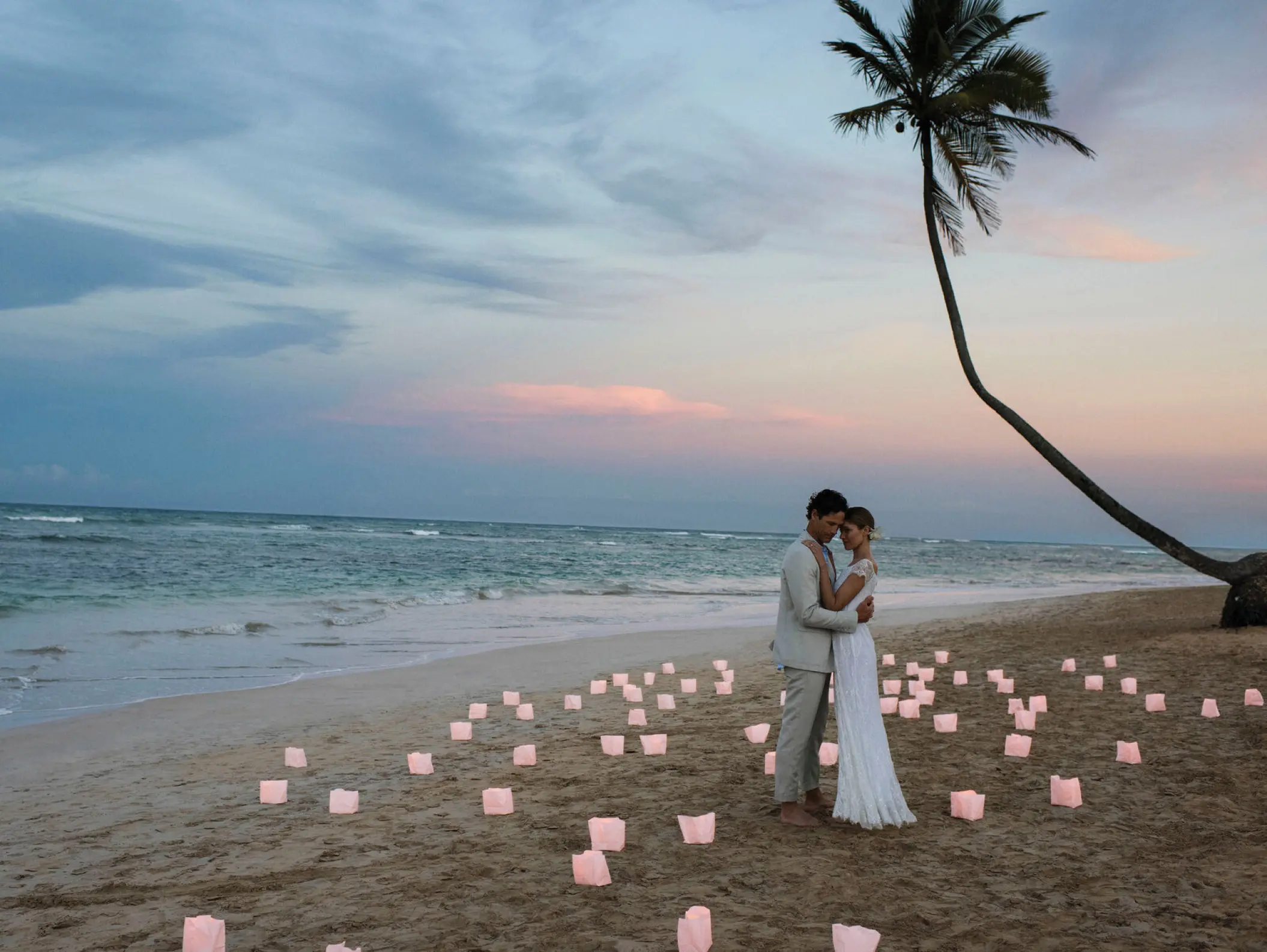 The bride and groom embracing on a beach with lanterns at Excellence El Carmen, Punta Cana