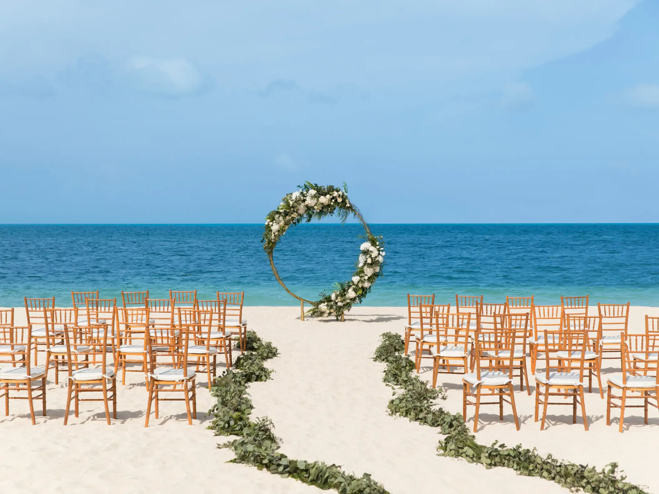 Beachfront wedding ceremony with circular floral arch at Excellence Playa Mujeres, Cancun