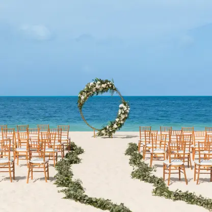 Beachfront wedding ceremony with circular floral arch at Excellence Playa Mujeres, Cancun