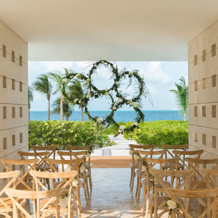 Stone gazebo wedding ceremony with floral ring backdrop at Excellence Playa Mujeres, Cancun