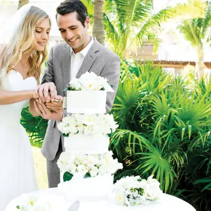 Bride and groom cutting a tiered white wedding cake at Excellence Playa Mujeres, Cancun