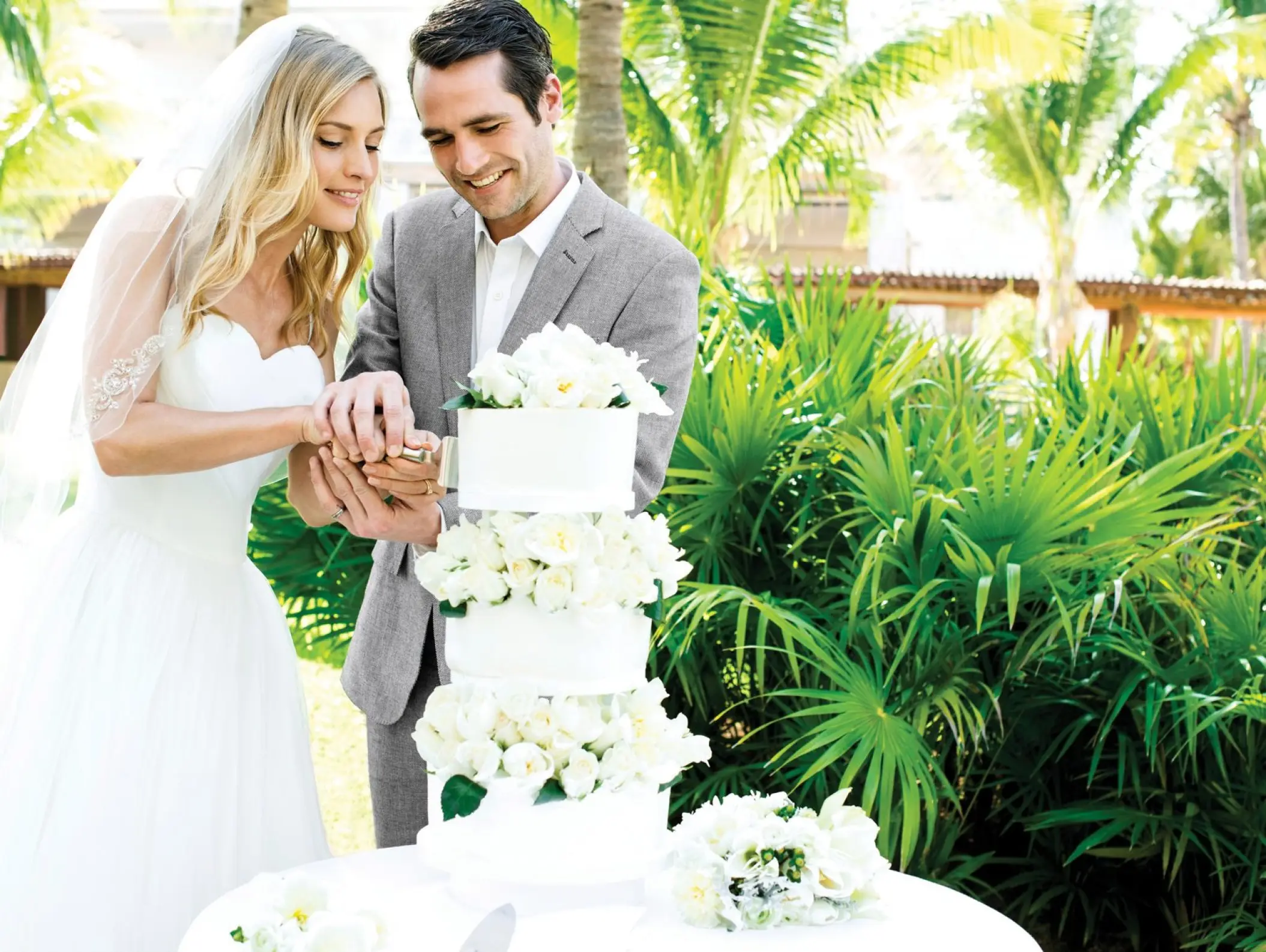 Bride and groom cutting a tiered white wedding cake at Excellence Playa Mujeres, Cancun