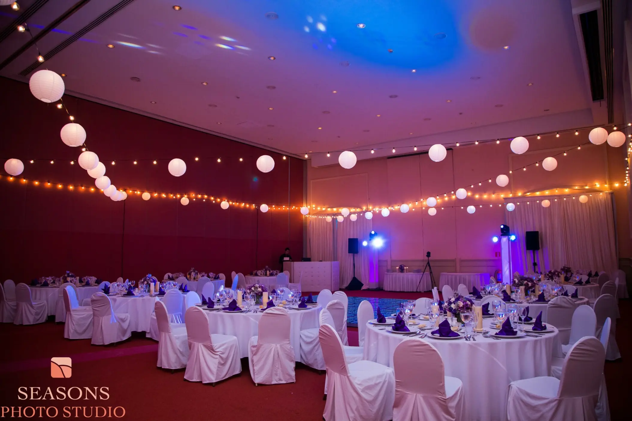 Indoor wedding reception with string lights and round tables at Excellence Riviera Cancun, Riviera Maya
