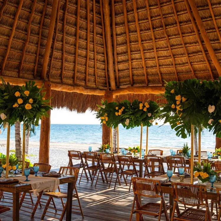 Palapa beach wedding reception with floral centerpieces at Excellence Riviera Cancun, Riviera Maya