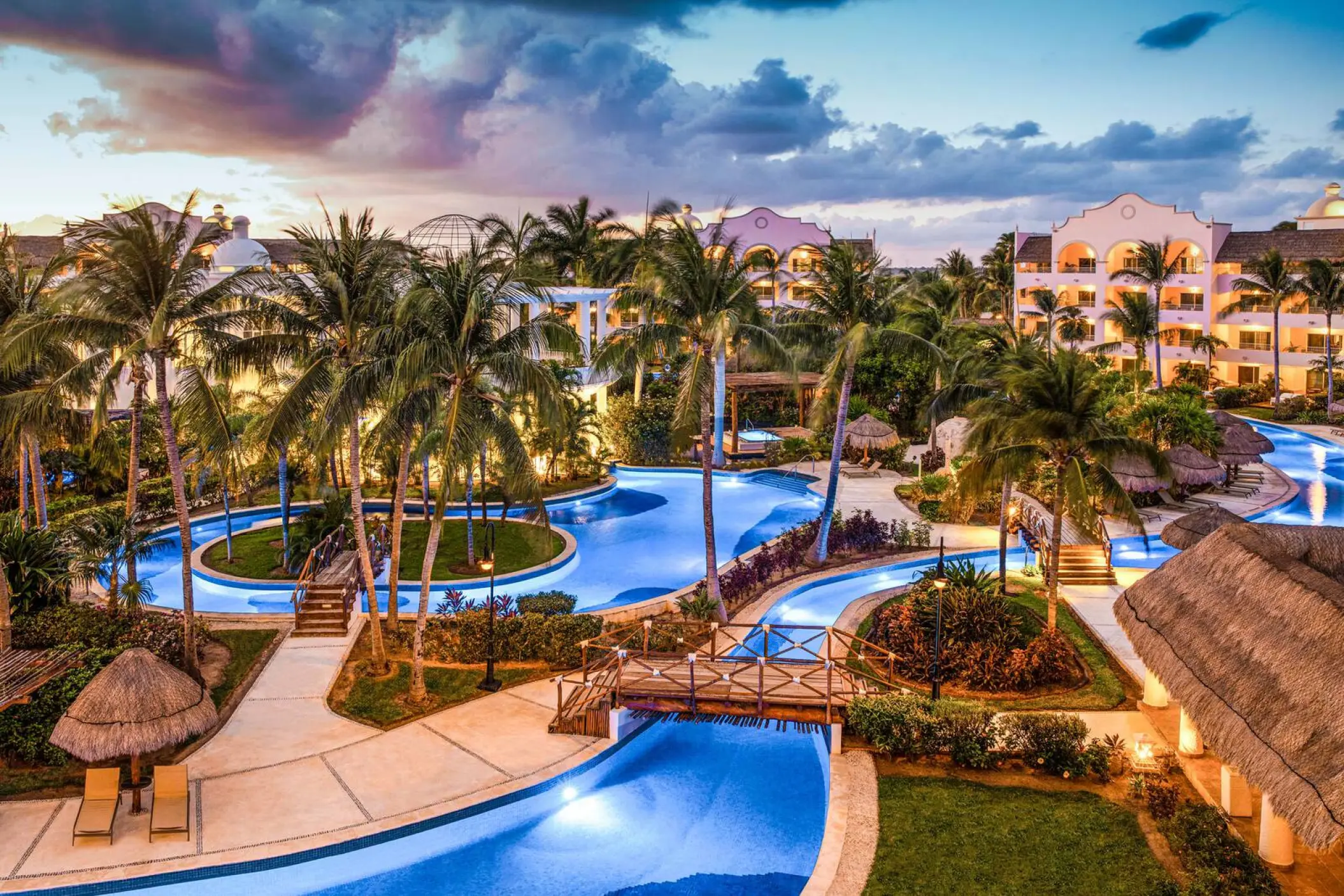 Dusk overview of pools, palm trees and gardens at Excellence Riviera Cancun, Riviera Maya