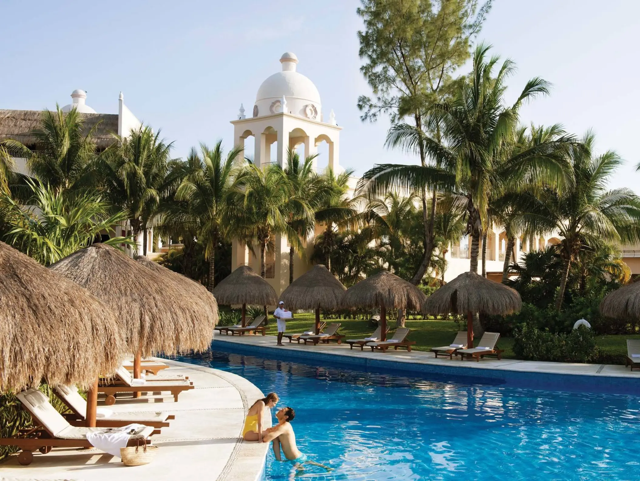 Couple by the winding outdoor pool and palapas at Excellence Riviera Cancun, Riviera Maya