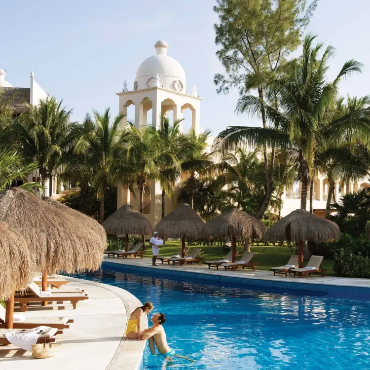 Couple by the winding outdoor pool and palapas at Excellence Riviera Cancun, Riviera Maya