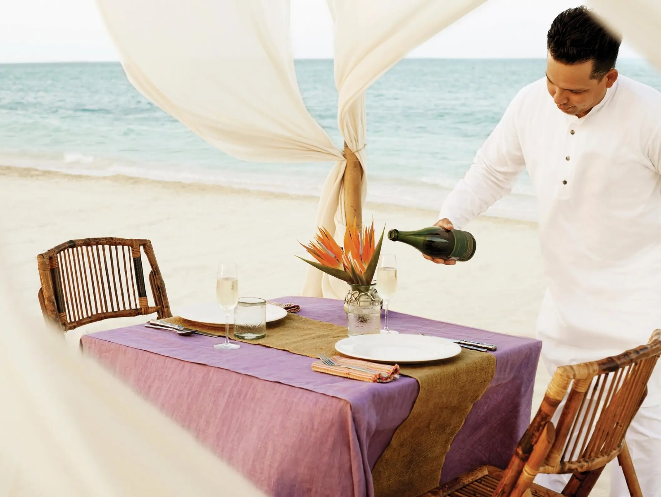 Server pouring champagne at a private beach dinner at Excellence Riviera Cancun, Riviera Maya