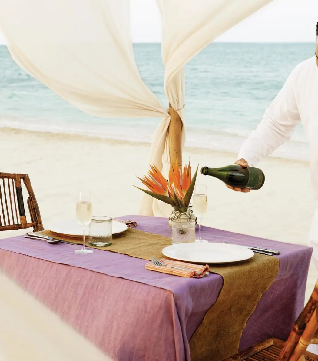 Server pouring champagne at a private beach dinner at Excellence Riviera Cancun, Riviera Maya