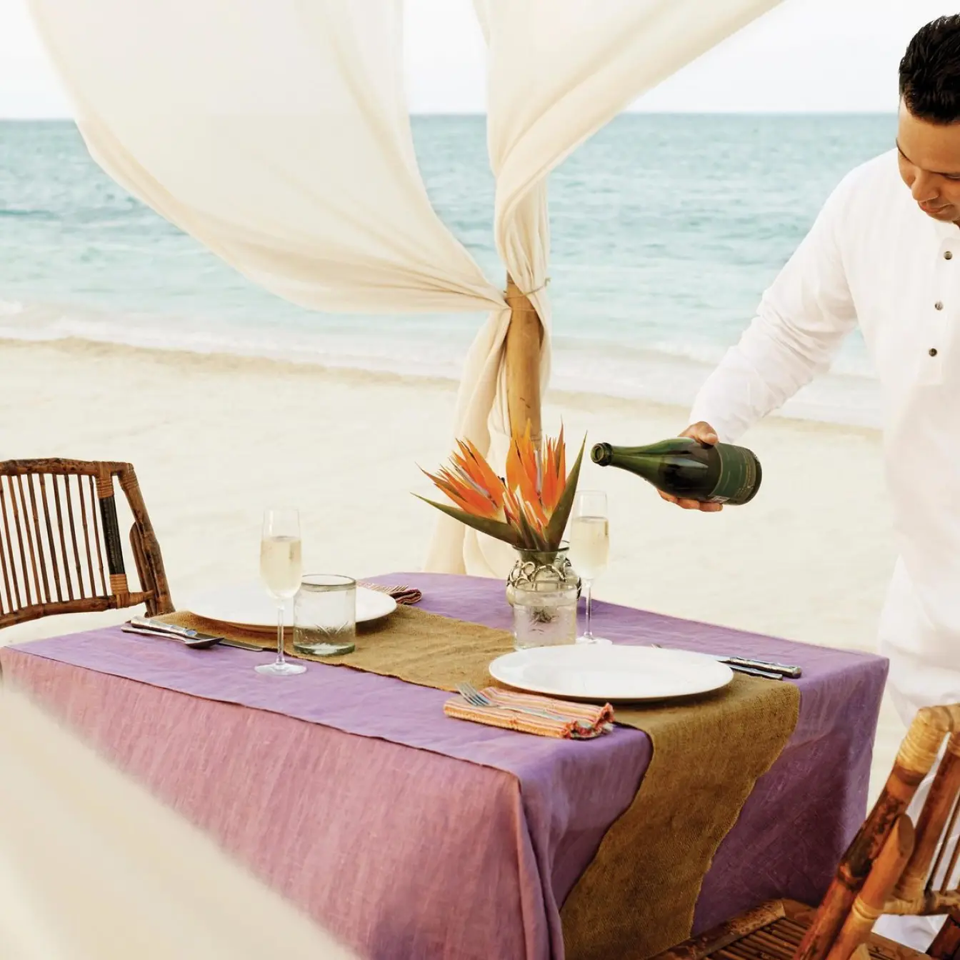 Server pouring champagne at a private beach dinner at Excellence Riviera Cancun, Riviera Maya