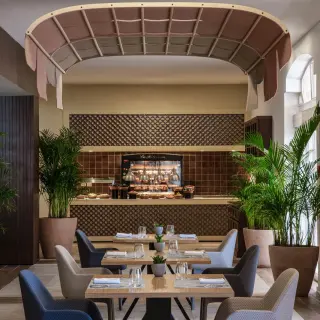 Modern restaurant dining room with potted palms at Excellence Riviera Cancun, Riviera Maya